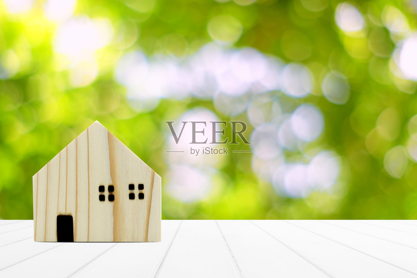 白色木桌上的木制迷你房子和花园背景中的美丽散景，有文字空间。照片摄影图片