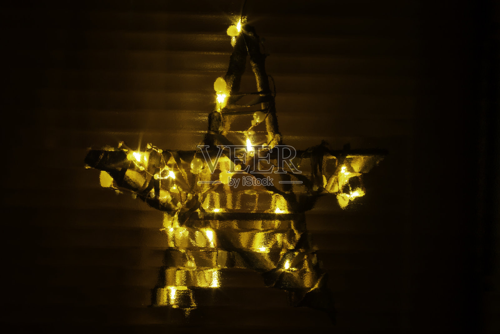 五角星与圣诞装置灯通过波纹玻璃看到照片摄影图片