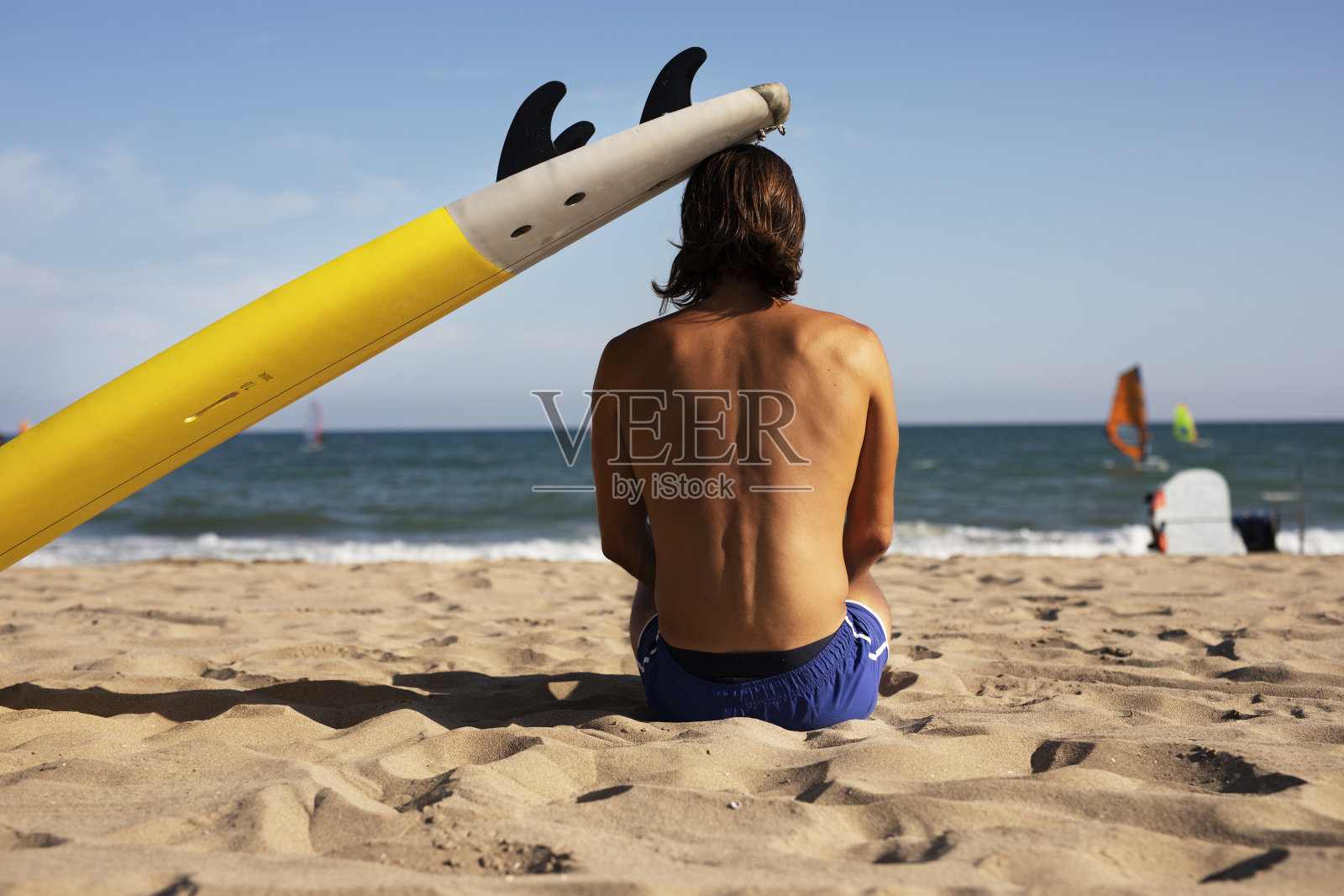 海滩上一个拿着冲浪板的年轻人。照片摄影图片