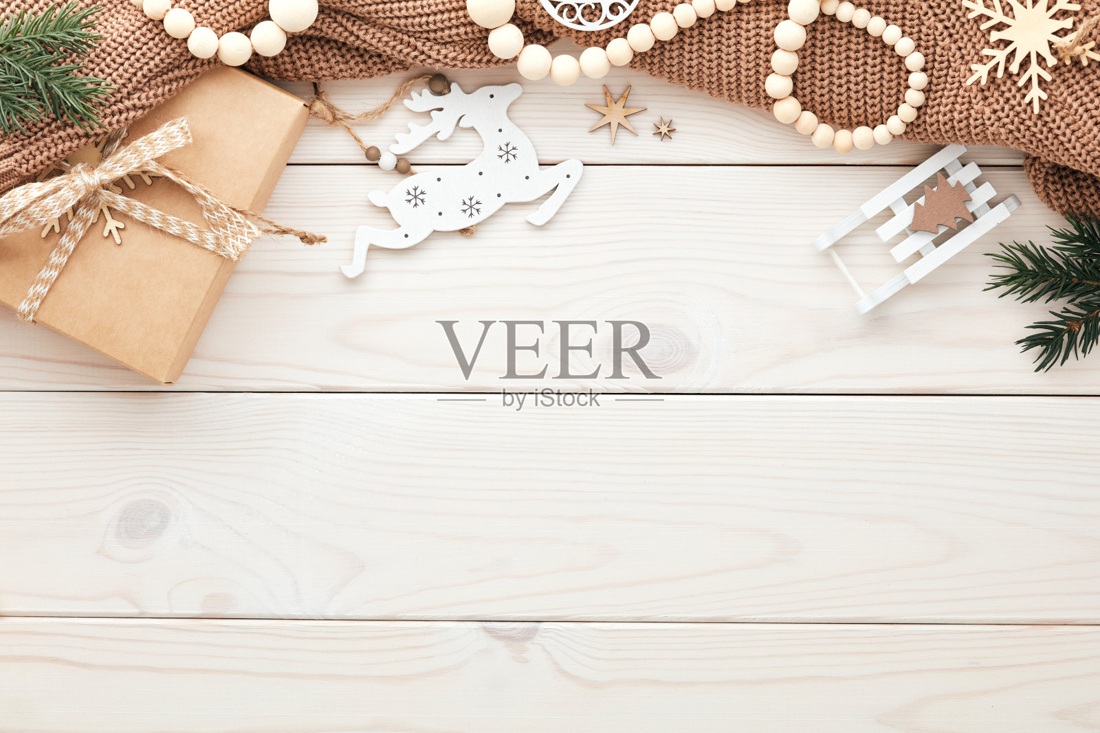 圣诞帧。针织毛衣，北欧圣诞装饰品，礼品盒，杉木树枝在白色木桌。从上面看。照片摄影图片