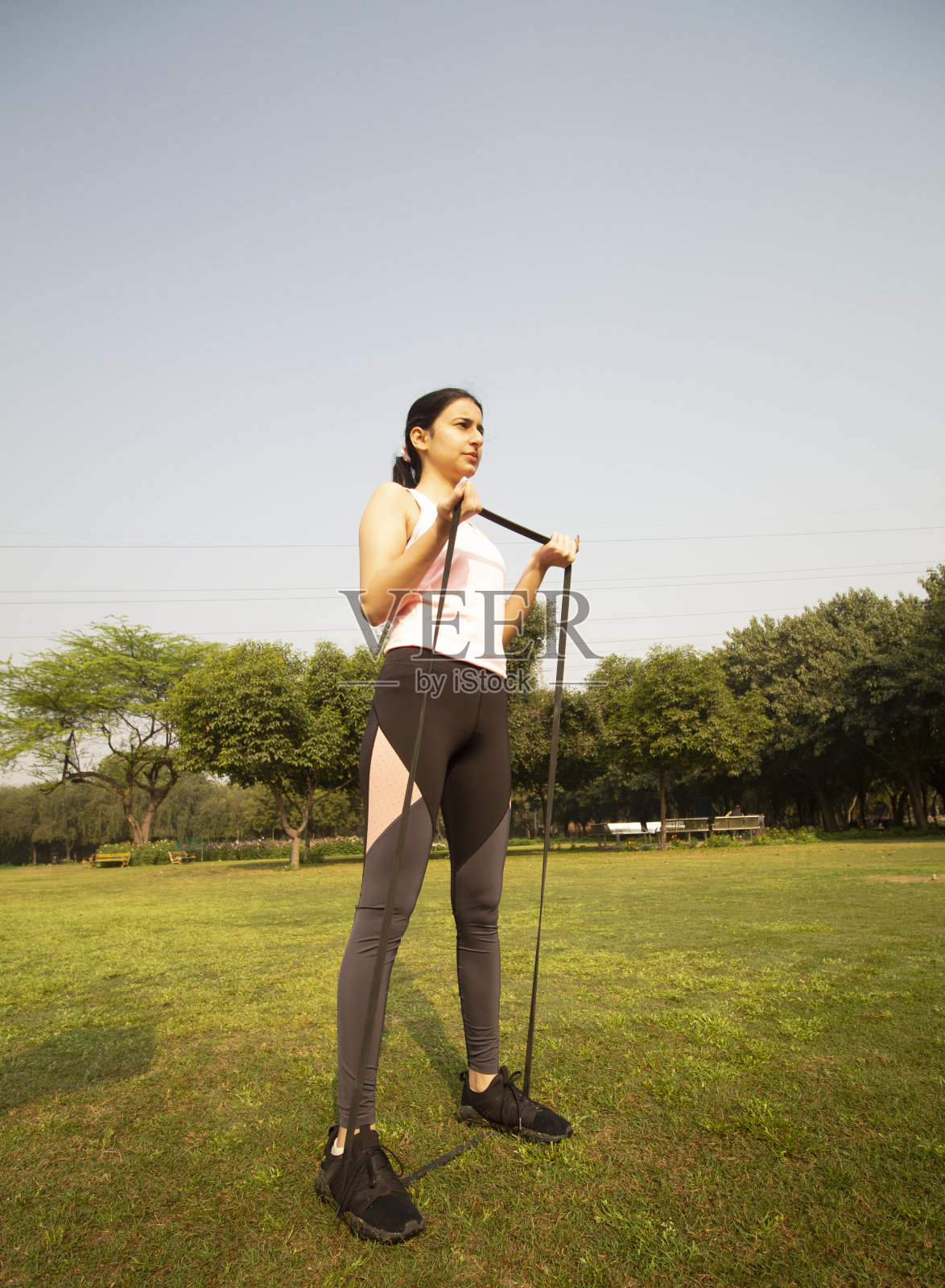 低角度的南亚女性拉伸与阻力带-一个健康的生活方式的概念照片摄影图片