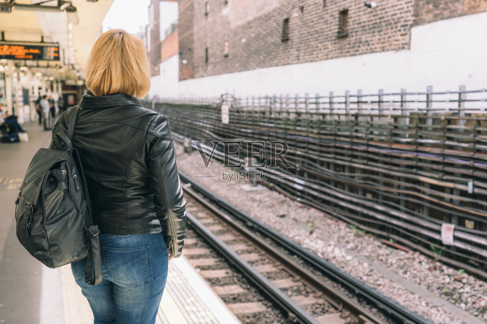一个背着背包的年轻女性站在站台上的后视图照片摄影图片
