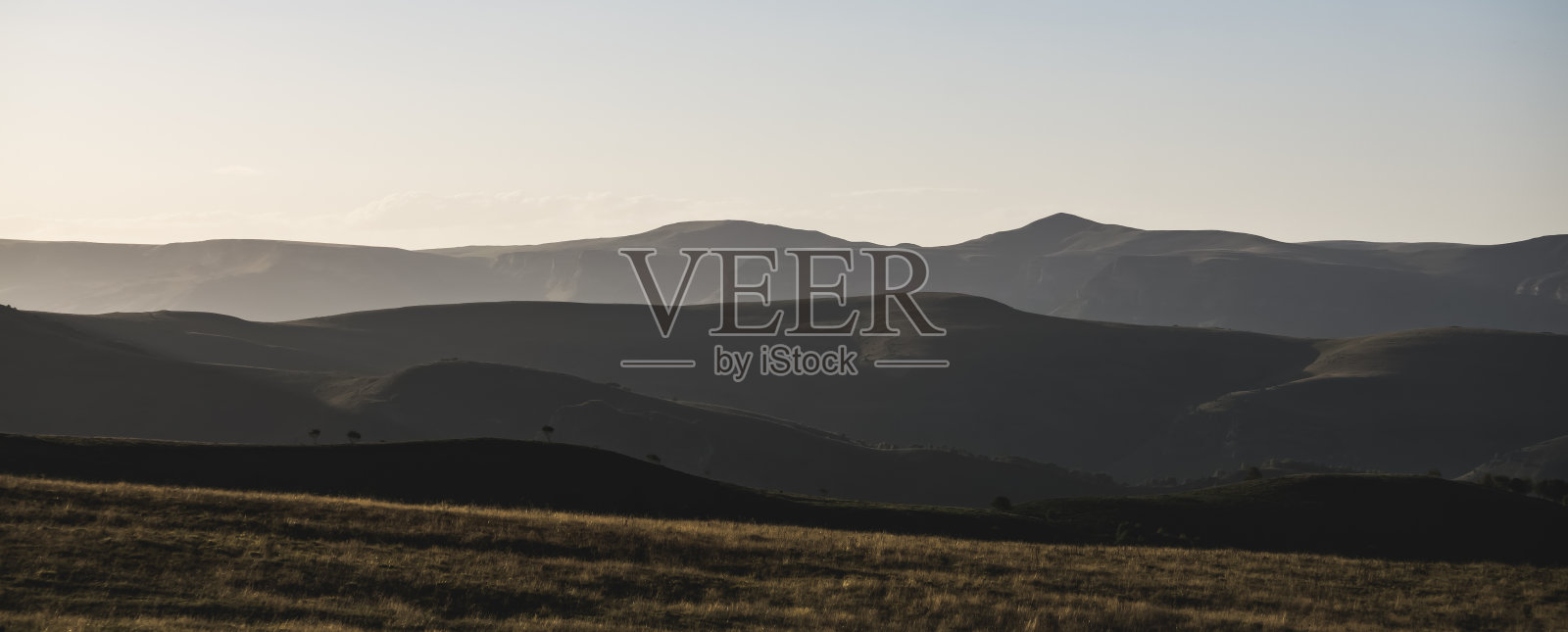 山脉的全景，丘陵和植被在上面，在傍晚的夕阳照明照片摄影图片