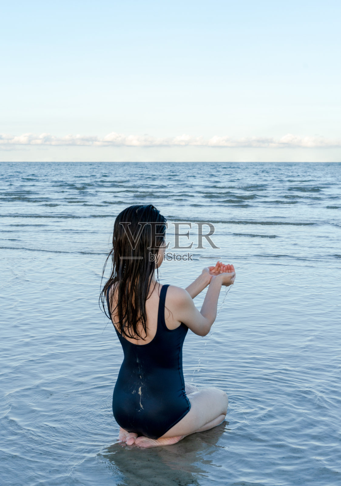 一名女子跪在浅水中照片摄影图片