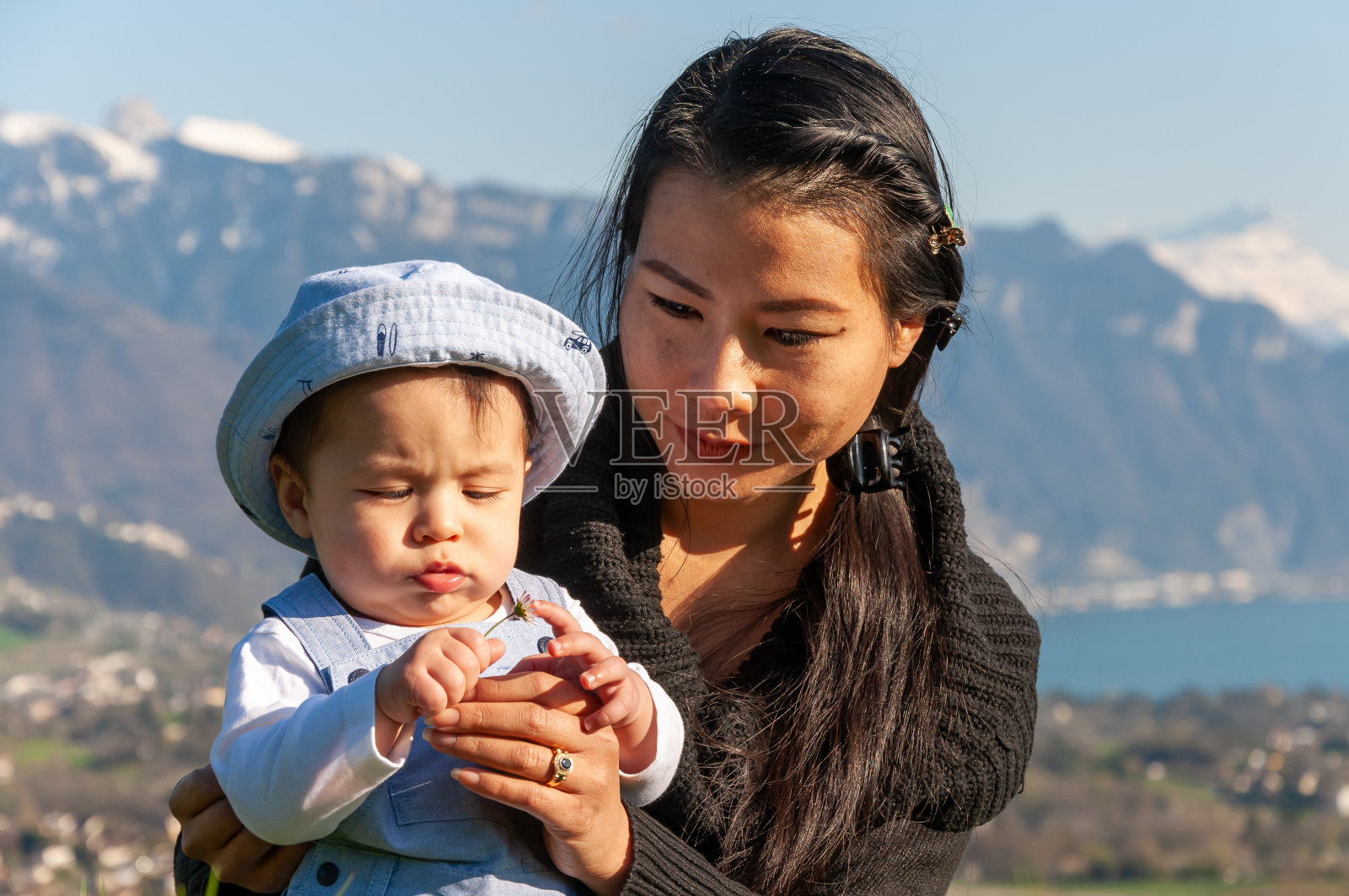 在瑞士日内瓦湖附近，一位亚洲母亲抱着她的男婴照片摄影图片
