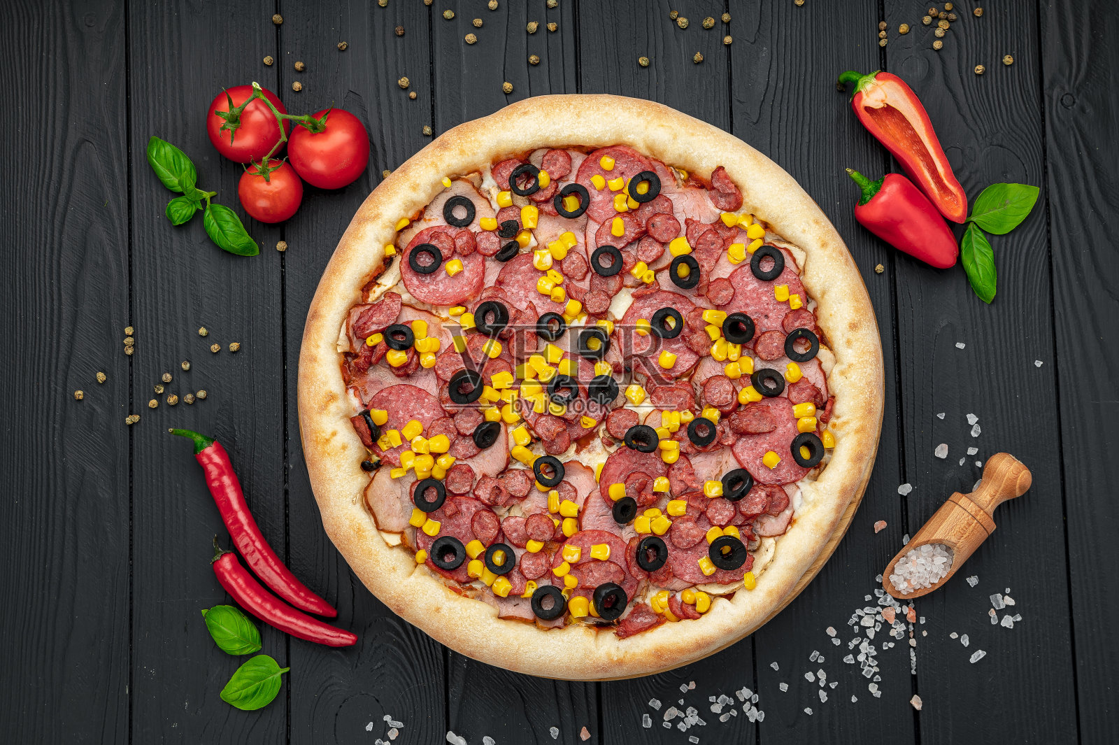 美味又大的披萨，里面有不同种类的肉。披萨配香肠、火腿、玉米和橄榄。照片摄影图片