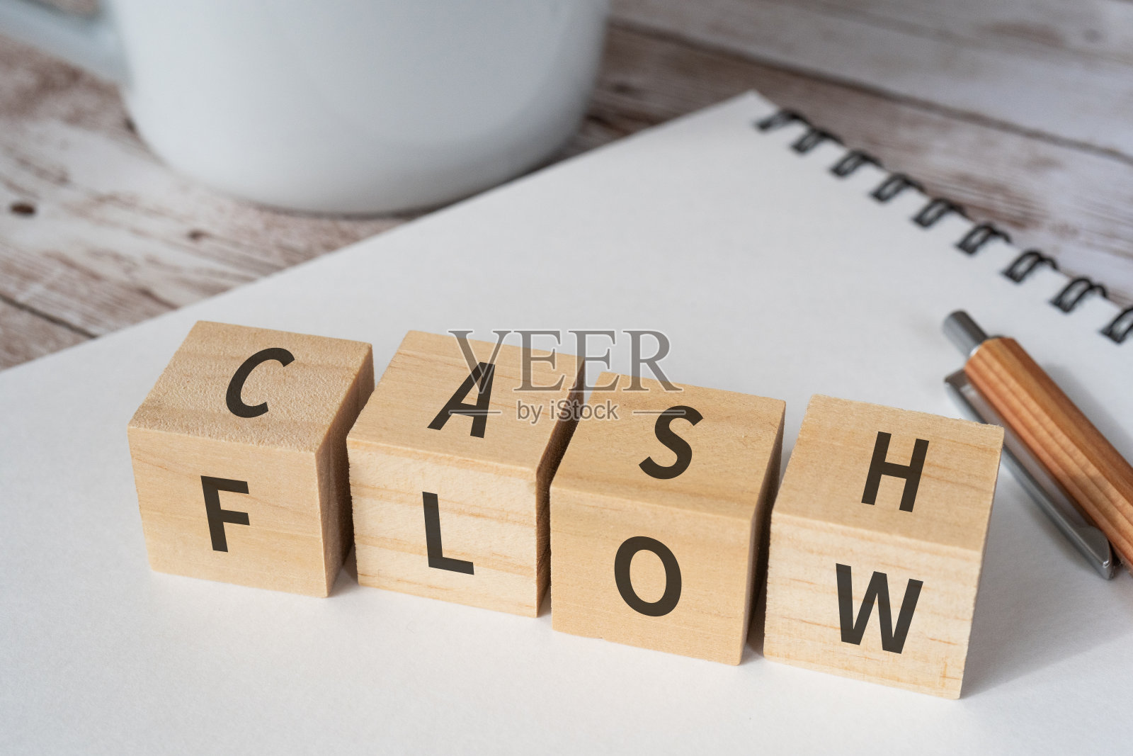 木块与“现金流”文本的概念，一支笔，一个笔记本，和一个杯子。照片摄影图片