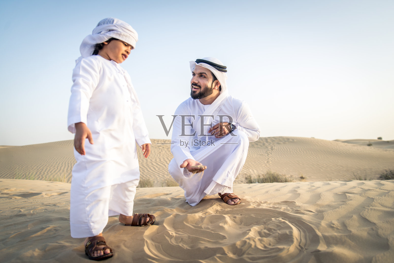 阿拉伯男子和儿子在沙漠中玩耍照片摄影图片