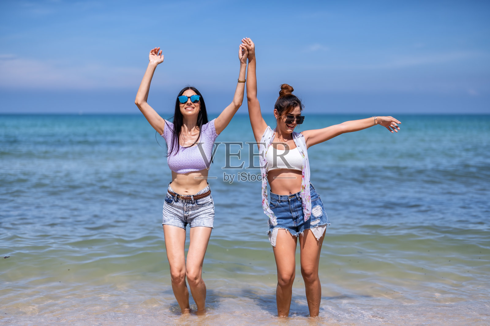 美丽的女孩友谊享受嬉笑玩乐在蓝色的大海和波手白色的沙滩上照片摄影图片