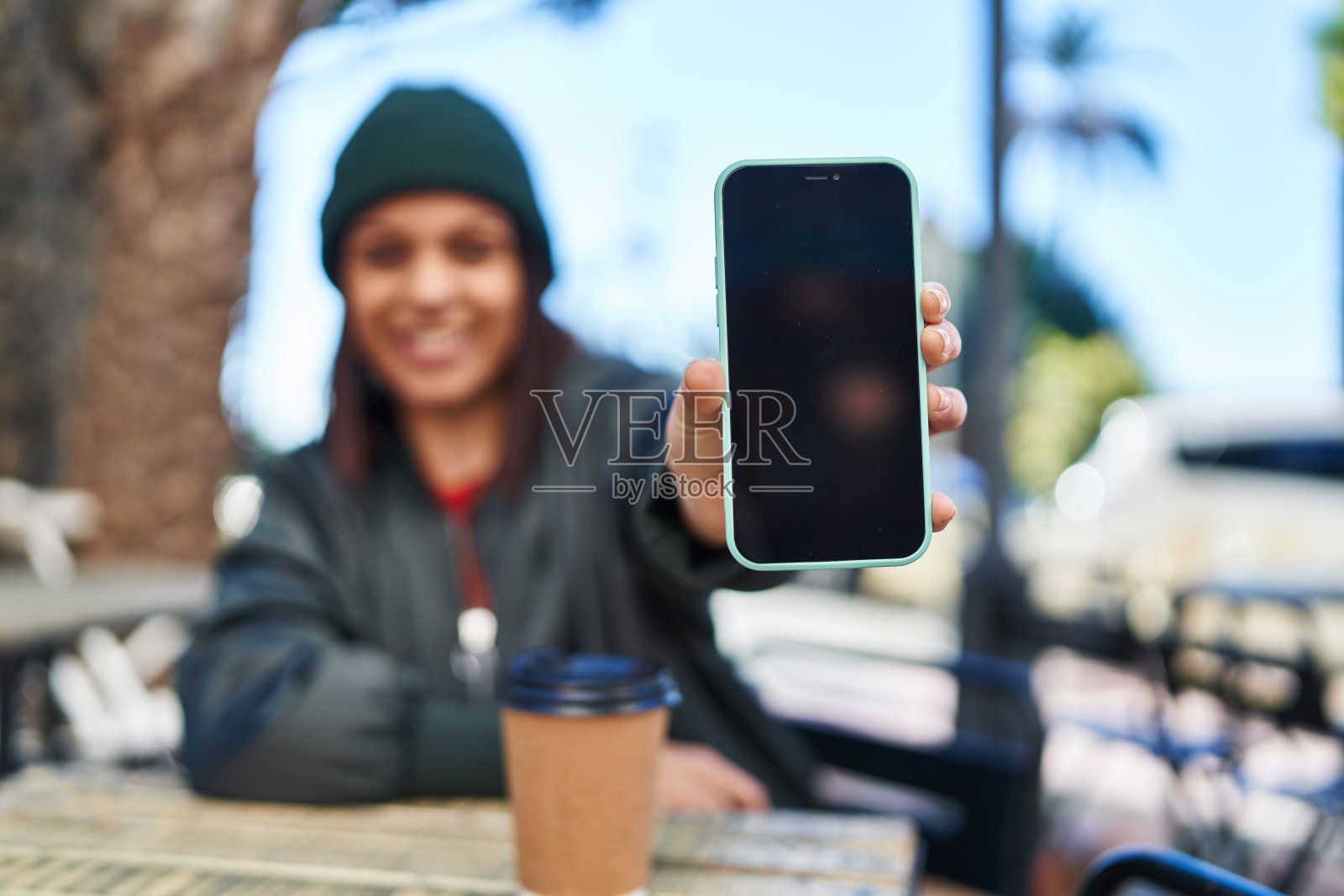 年轻美丽的西班牙妇女显示屏幕智能手机坐在咖啡馆露台的桌子上照片摄影图片