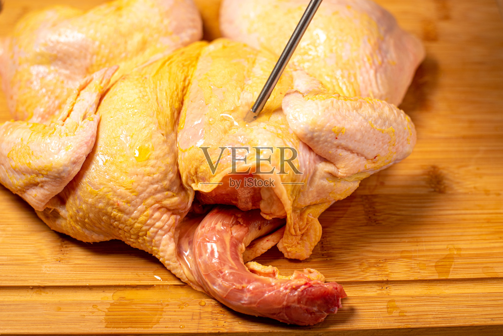 厨师在厨房里准备了一整只生鸡。一名男子为烧烤准备生鸡肉，将苹果酒注入肉中。照片摄影图片