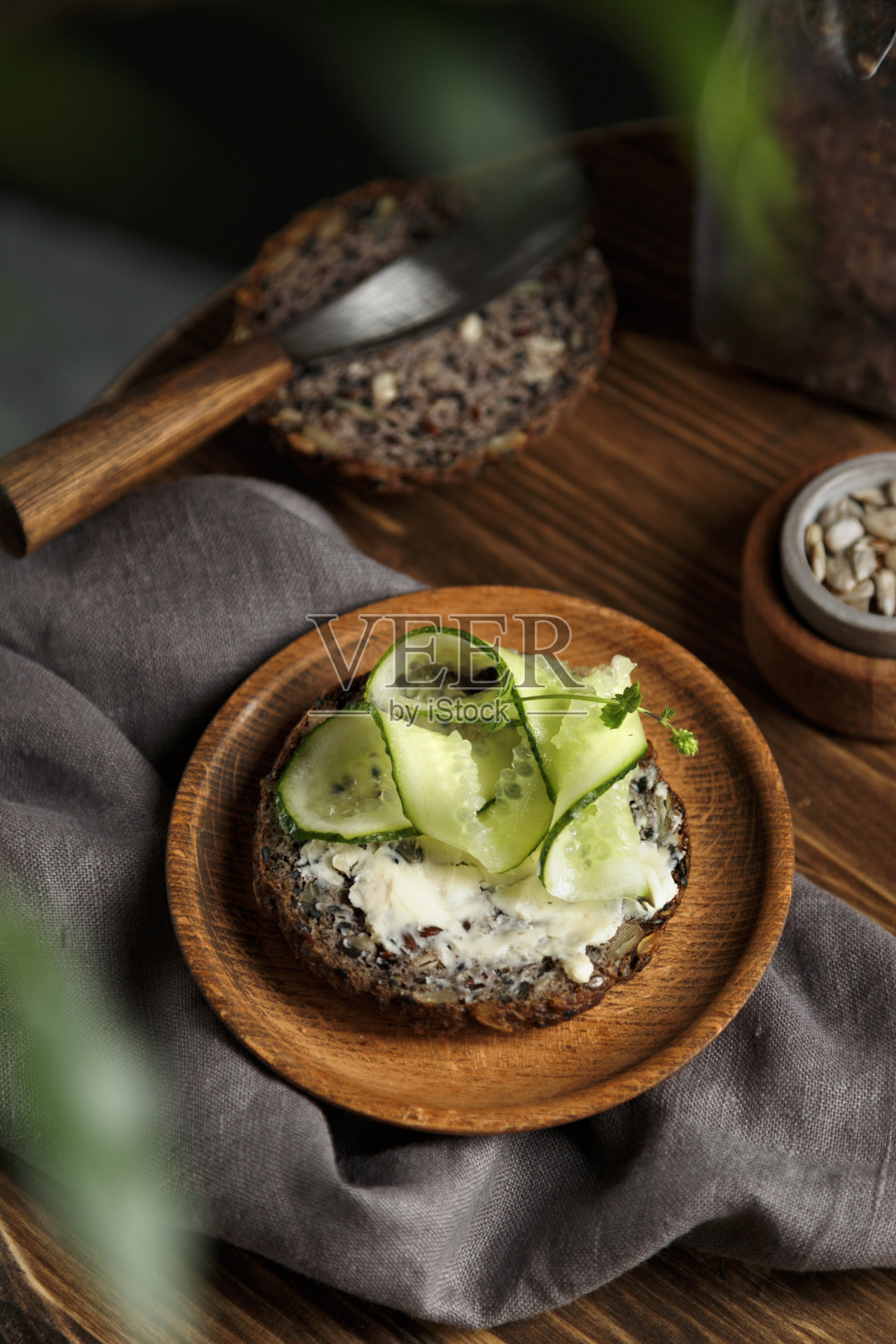 吐司配奶油芝士和切片黄瓜在全麦面包上。意式烤面包，盘子上的三明治和木制背景。照片摄影图片