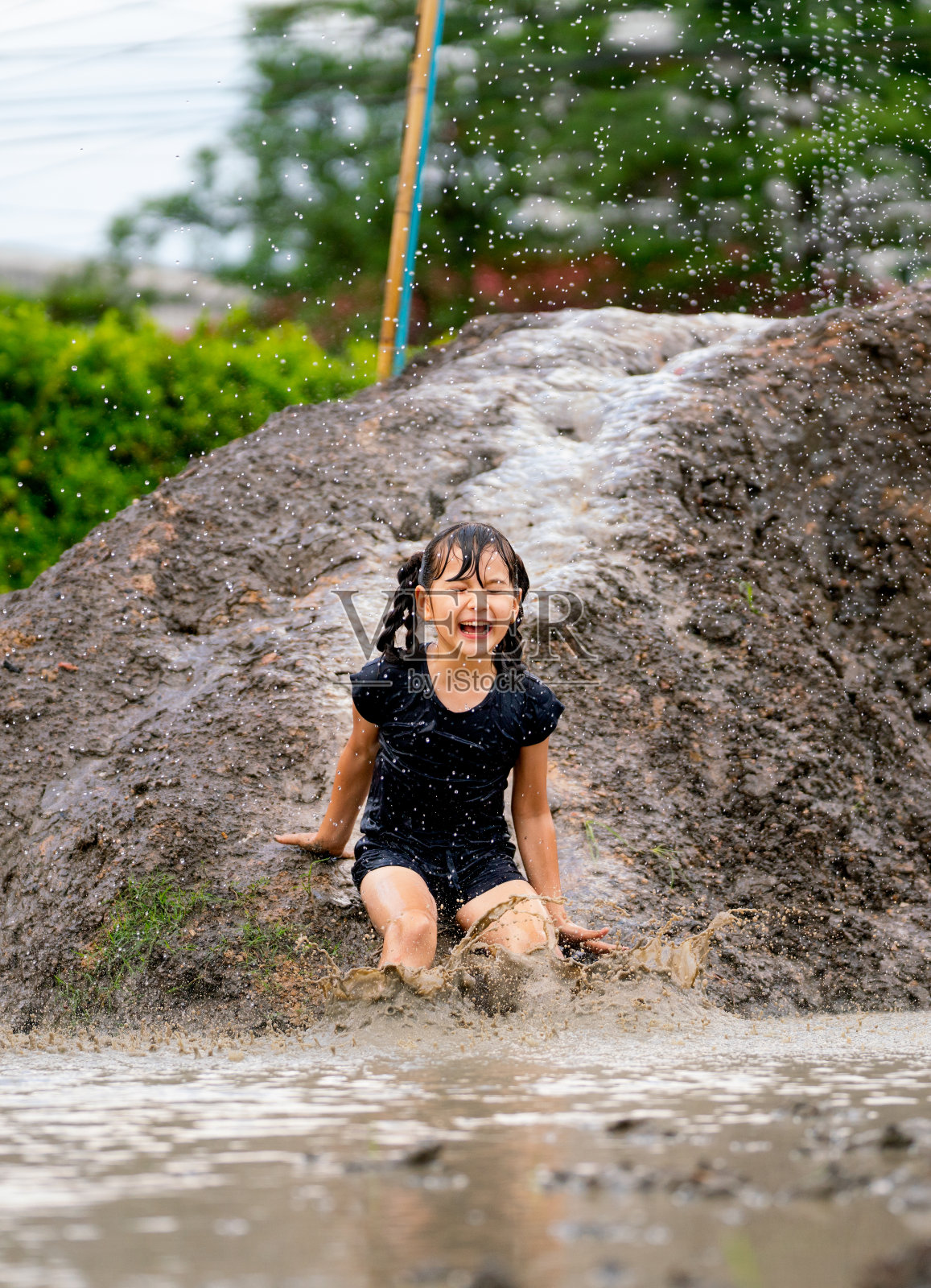 小女孩在公共操场上玩泥土滑车，笑着表示快乐。照片摄影图片