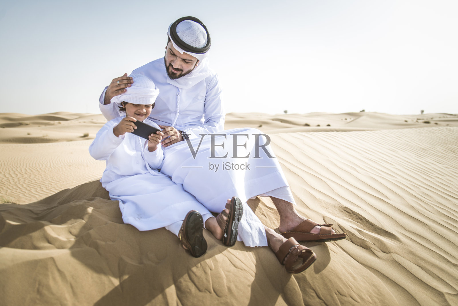 阿拉伯男子和儿子在沙漠中玩耍照片摄影图片