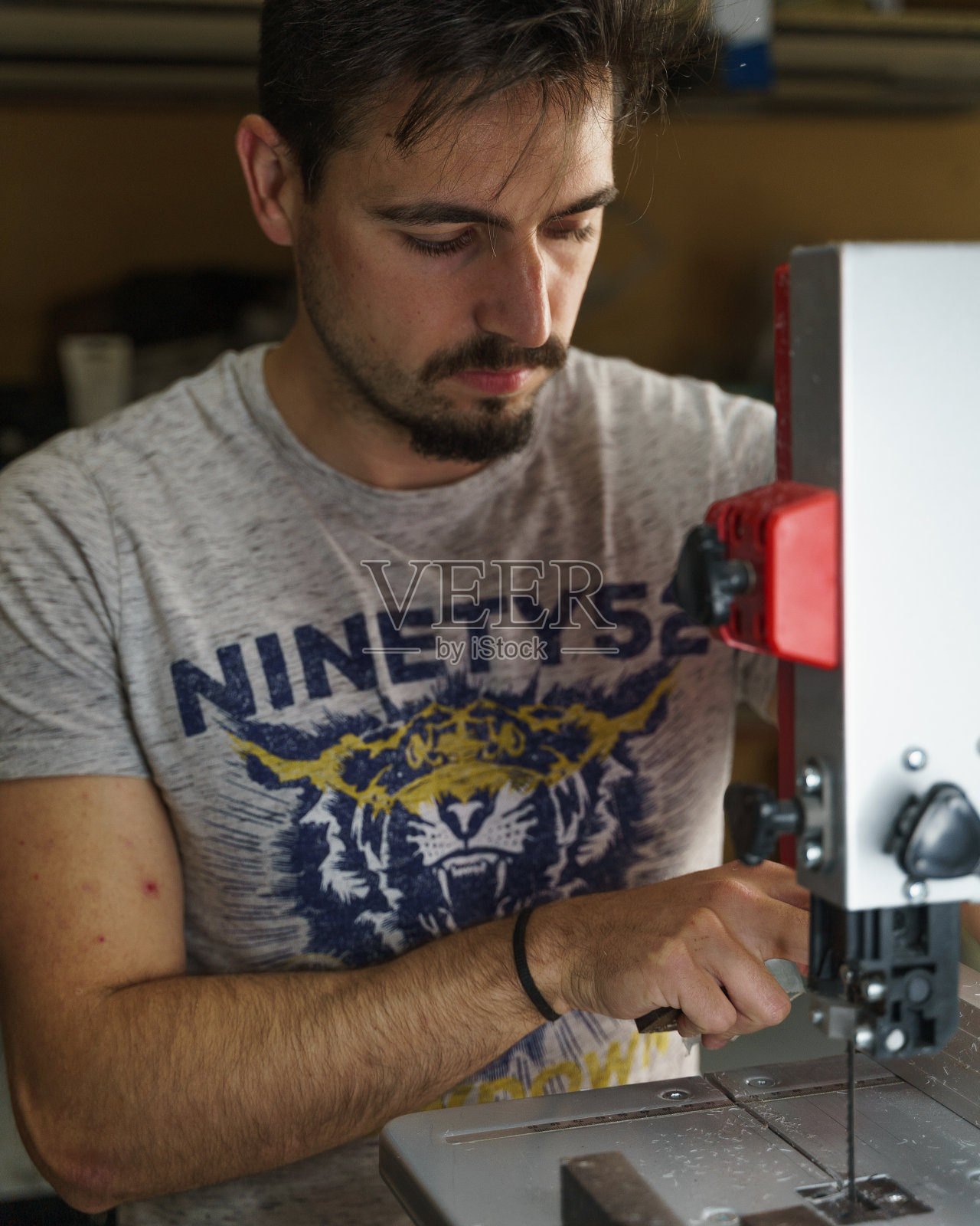 一个留着胡子的白人男子使用带锯机的垂直镜头照片摄影图片