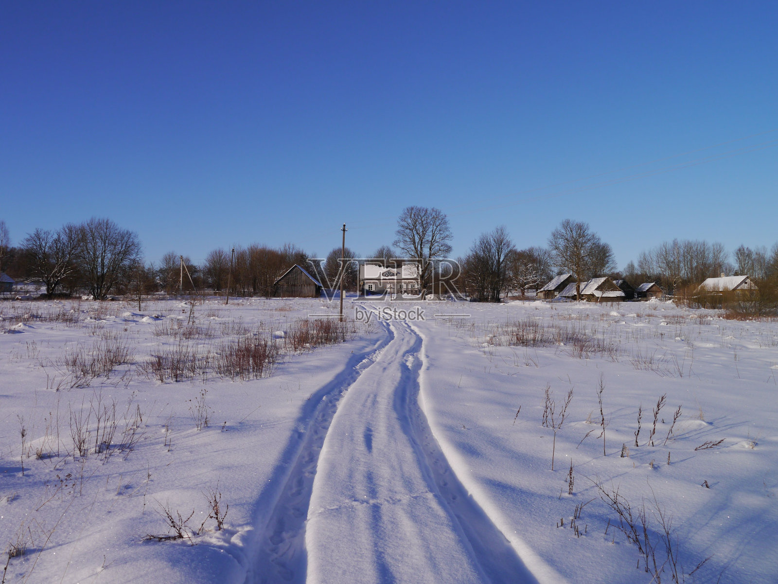 在阳光明媚的日子里，田野上的雪道通向无数的单层木屋照片摄影图片