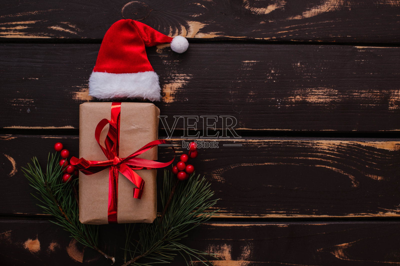 圣诞扁平礼品盒，圣诞老人帽子和圣诞云杉树枝在木制背景。照片摄影图片