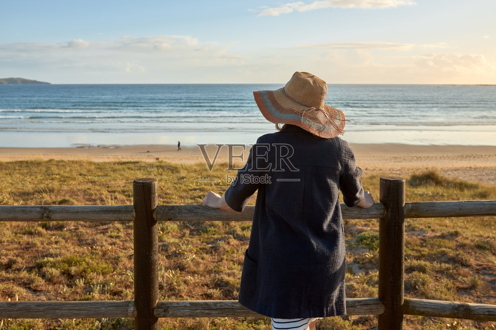 海滩上的女孩站在木栏杆上凝视着大海照片摄影图片