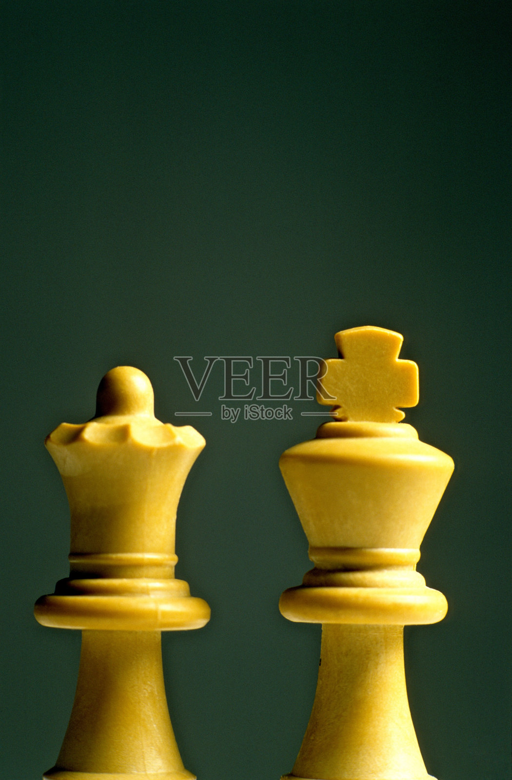 绿色背景上的白色国王和王后象棋棋子的垂直镜头照片摄影图片