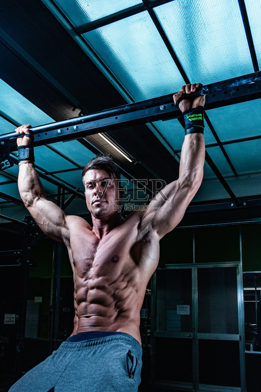一个健美的男性健美运动员挂在健身房的吧台上的垂直镜头照片摄影图片