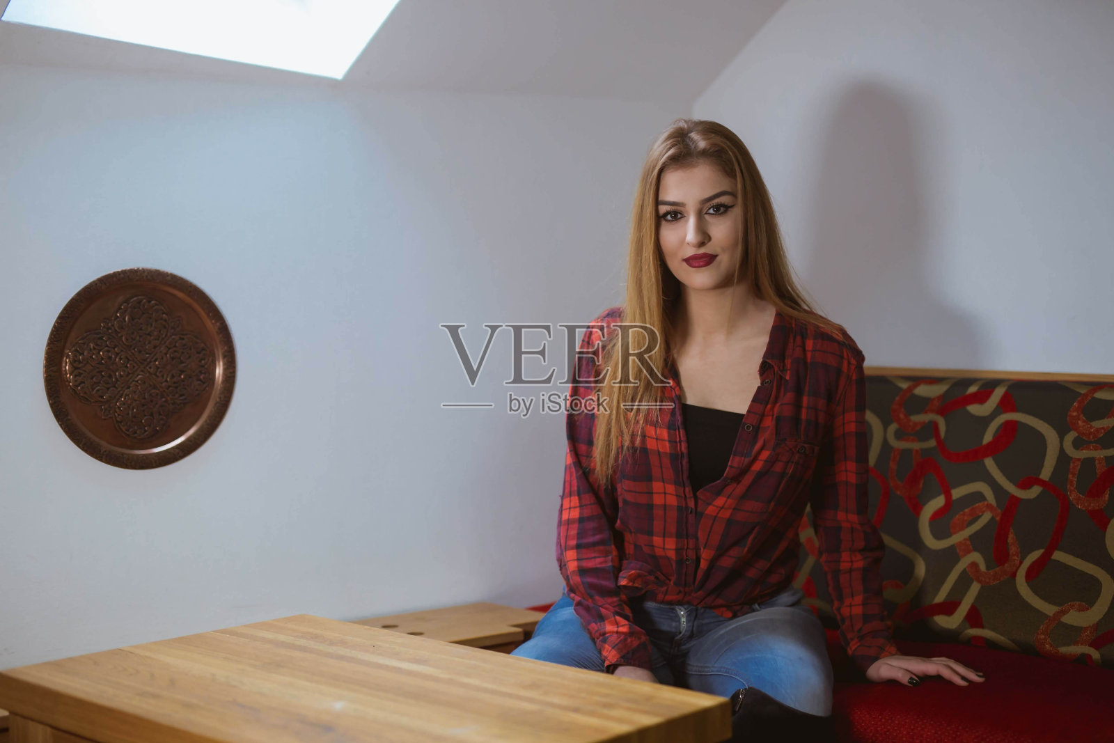 穿着红格子衬衫的白人女性坐在沙发上照片摄影图片