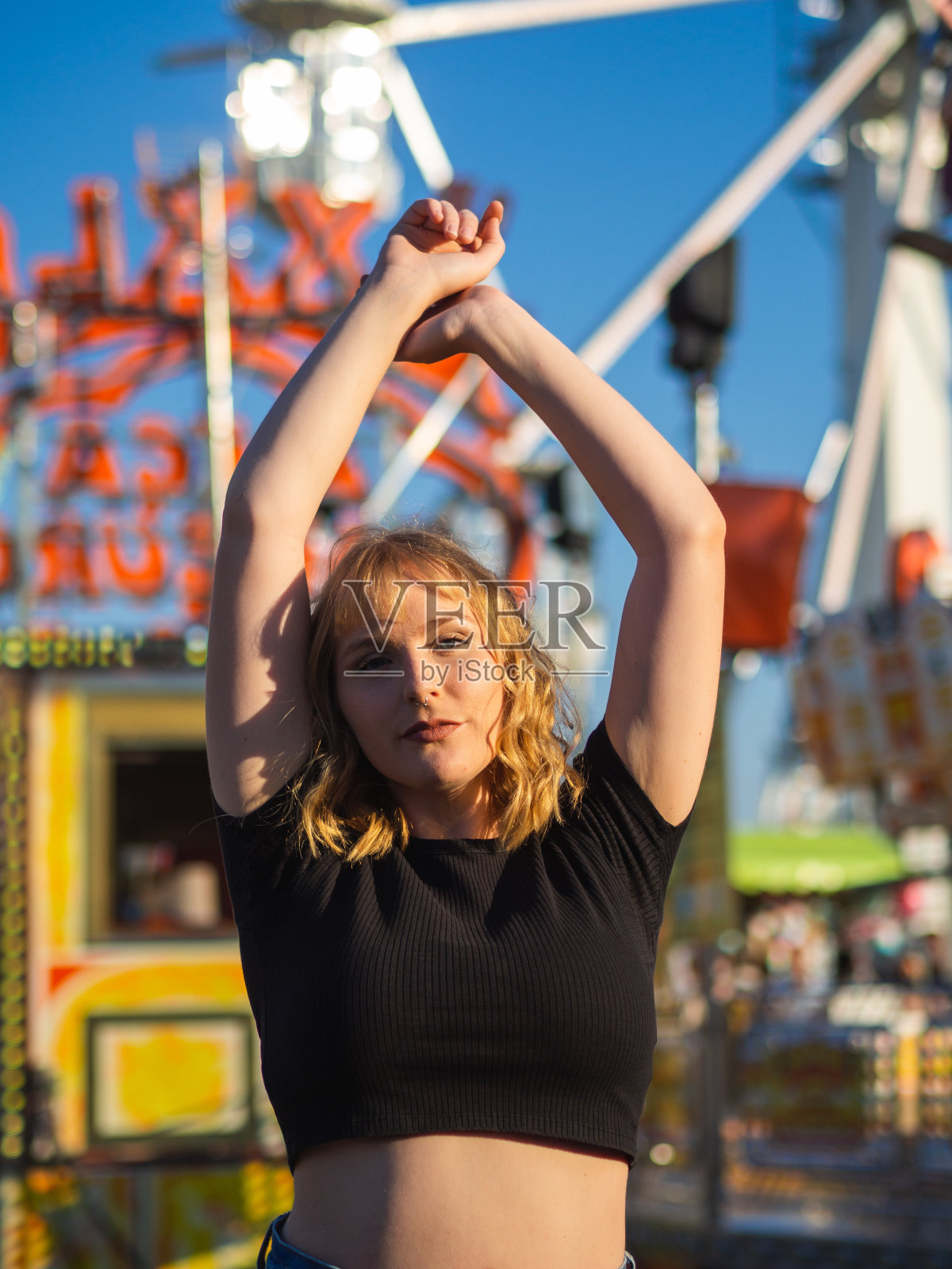 垂直拍摄的年轻金发快乐的女性在游乐园摆姿势照片摄影图片
