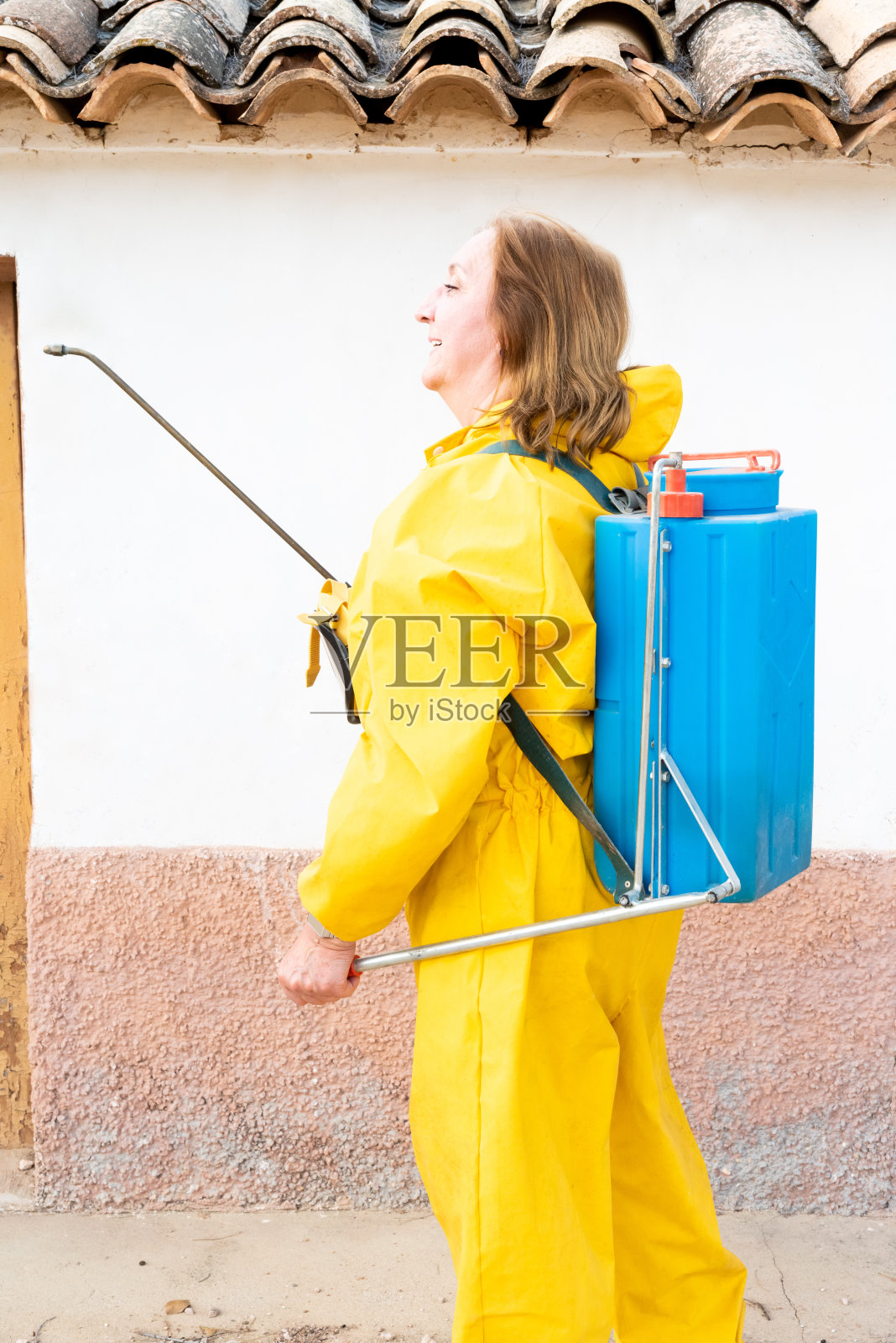 垂直拍摄的女性穿着化学防护服，同时使用特殊工具照片摄影图片