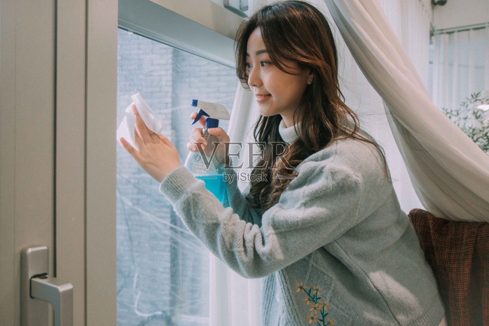 年轻的韩国女性正在清洁玻璃窗照片摄影图片