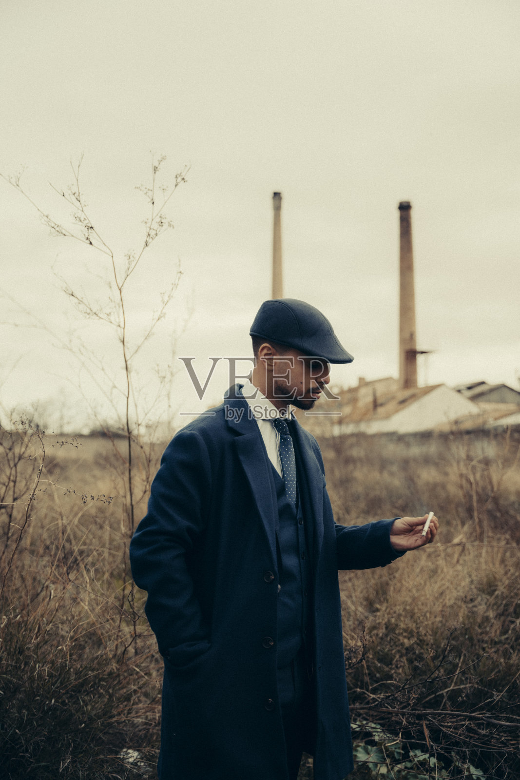 垂直拍摄的一个西班牙男性，穿着20世纪的复古黑帮服装，手里拿着一根烟照片摄影图片