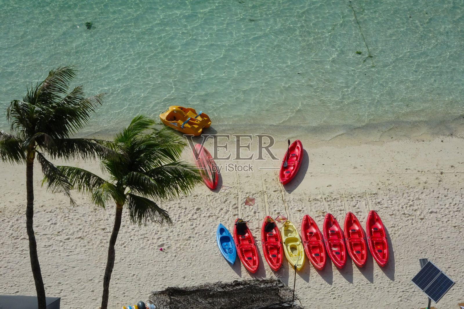 关岛图蒙海滩上的椰子树和色彩斑斓的独木舟照片摄影图片
