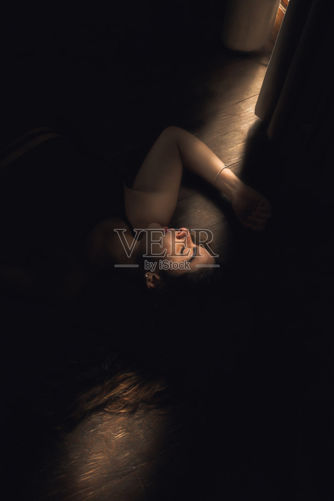 垂直拍摄的女性摆姿势躺在窗户的阴影照片摄影图片