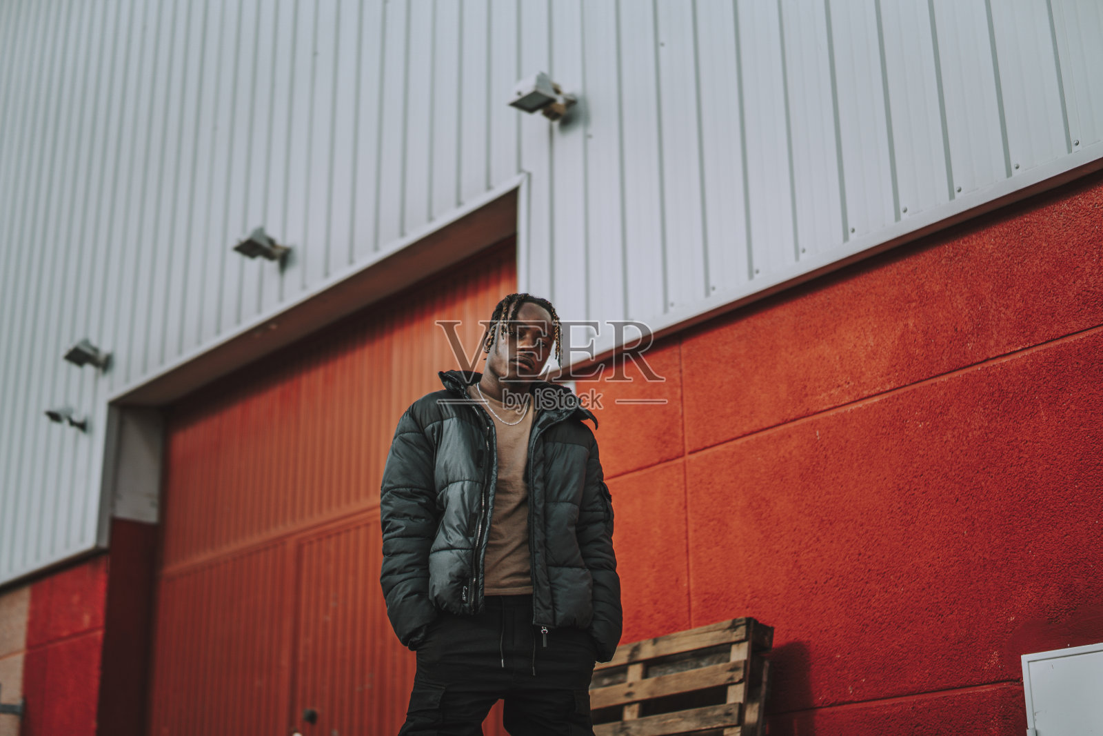 一个英俊时髦的西班牙男子戴着兜帽在建筑背景上摆姿势的低角度镜头照片摄影图片