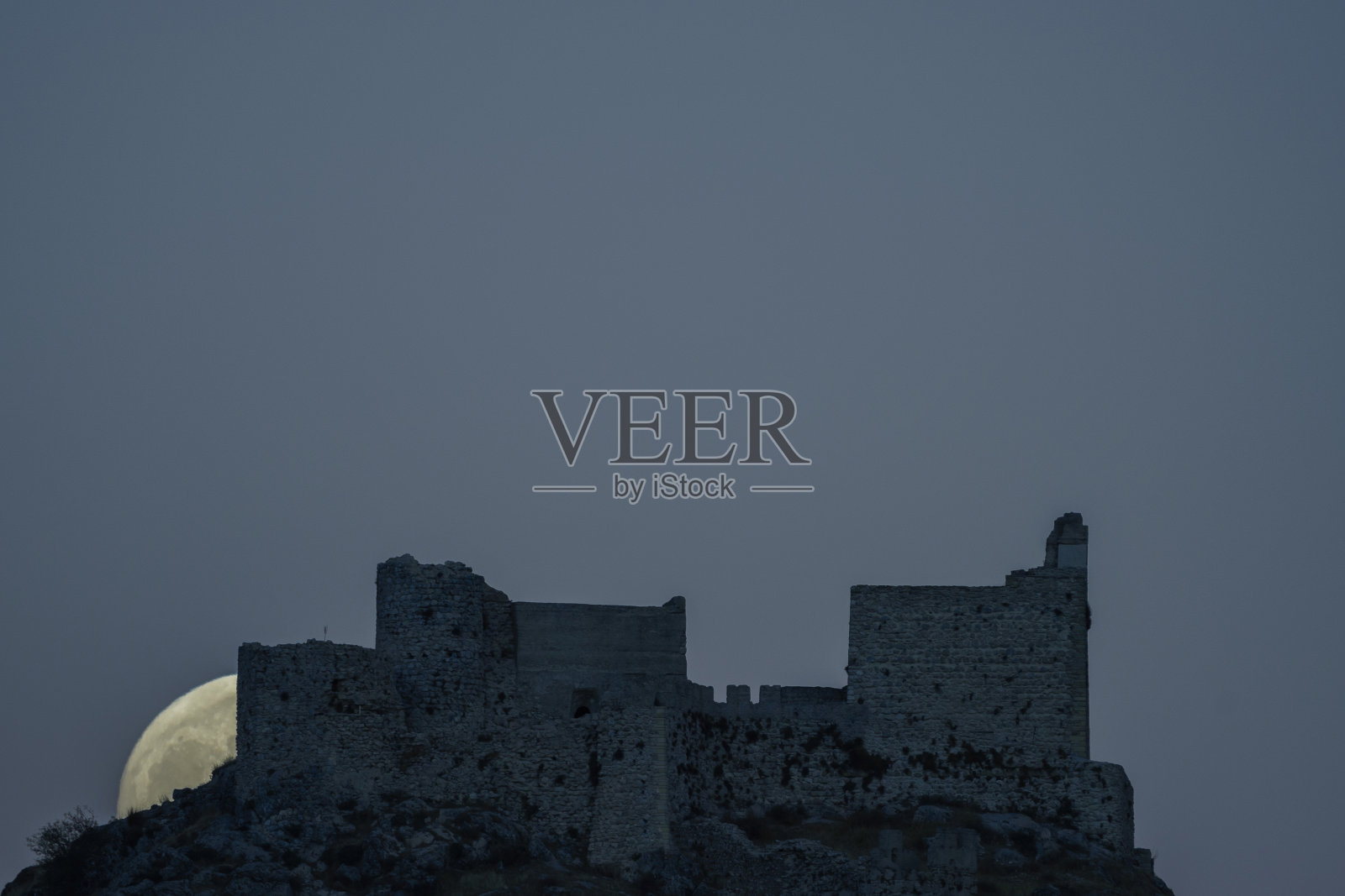 拍摄从城堡后面升起的满月照片摄影图片