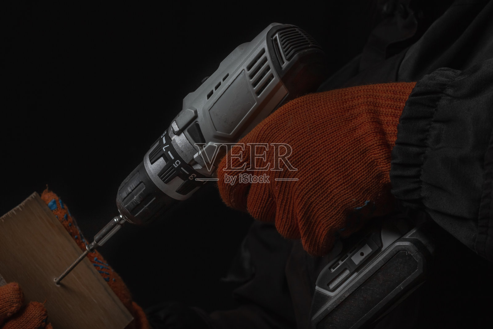 手持无绳电动螺丝刀与钻头螺钉和钻孔隔离在黑色背景照片摄影图片