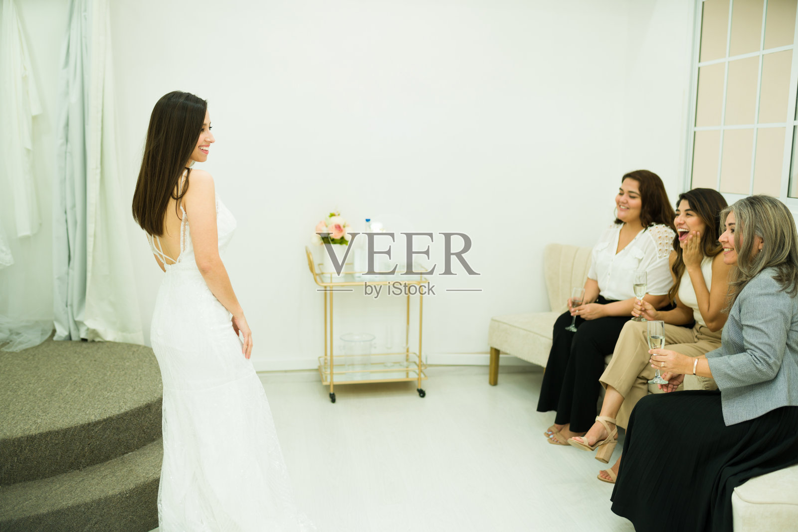 年轻女子向她的母亲和朋友们展示她美丽的裙子照片摄影图片