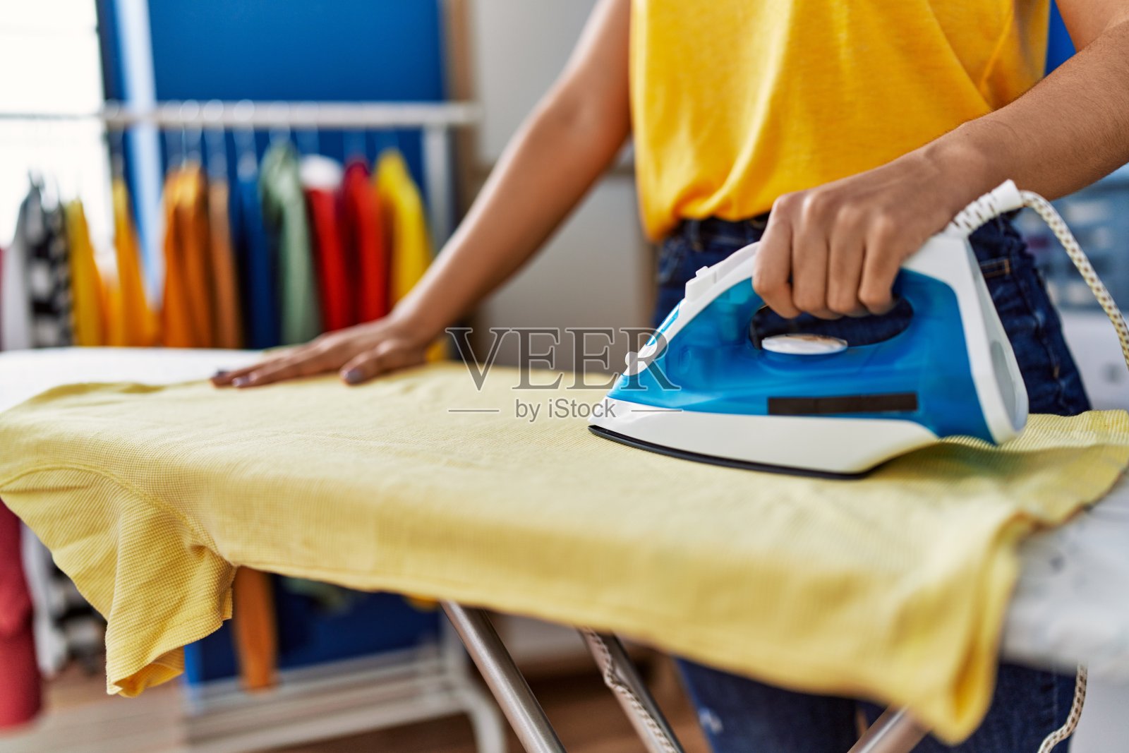 年轻的拉丁妇女微笑自信地熨烫衣服在洗衣房照片摄影图片