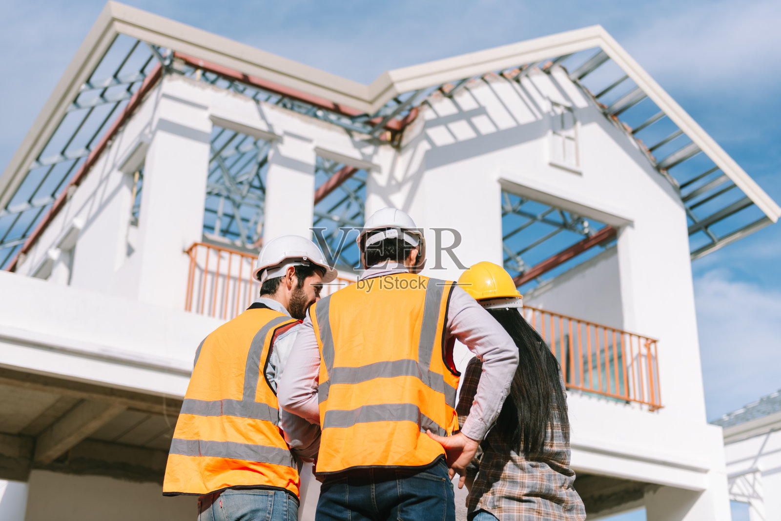 一群不同的人，戴着安全帽和安全装备的建筑工人在建筑工地一起工作。房地产行业。照片摄影图片