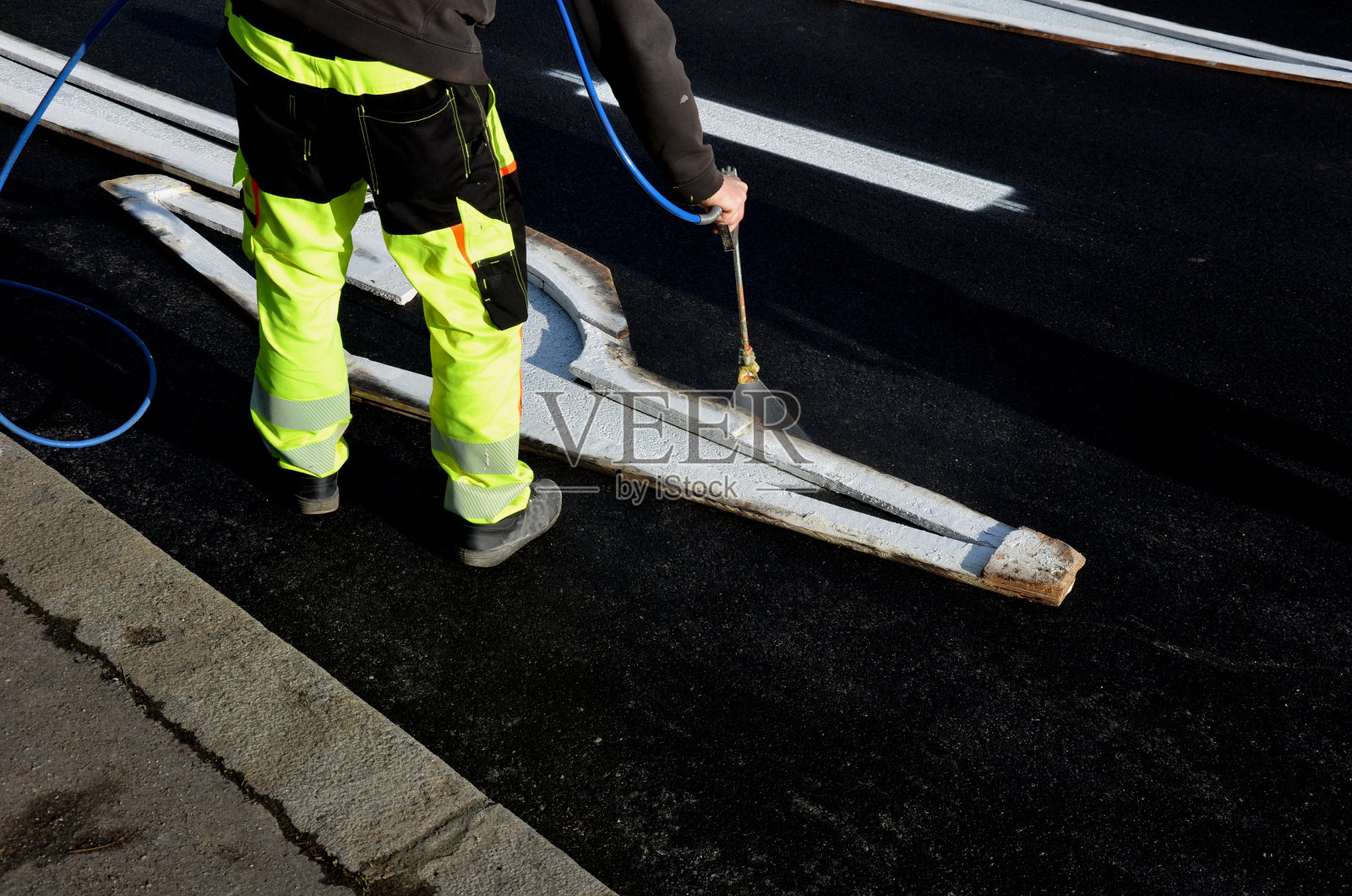 恢复与回旋处及十字路口的水平标志。他们用模板喷新符号。然后他们用沙子把它盖上颜料不粘轮，反光绿色的衣服照片摄影图片