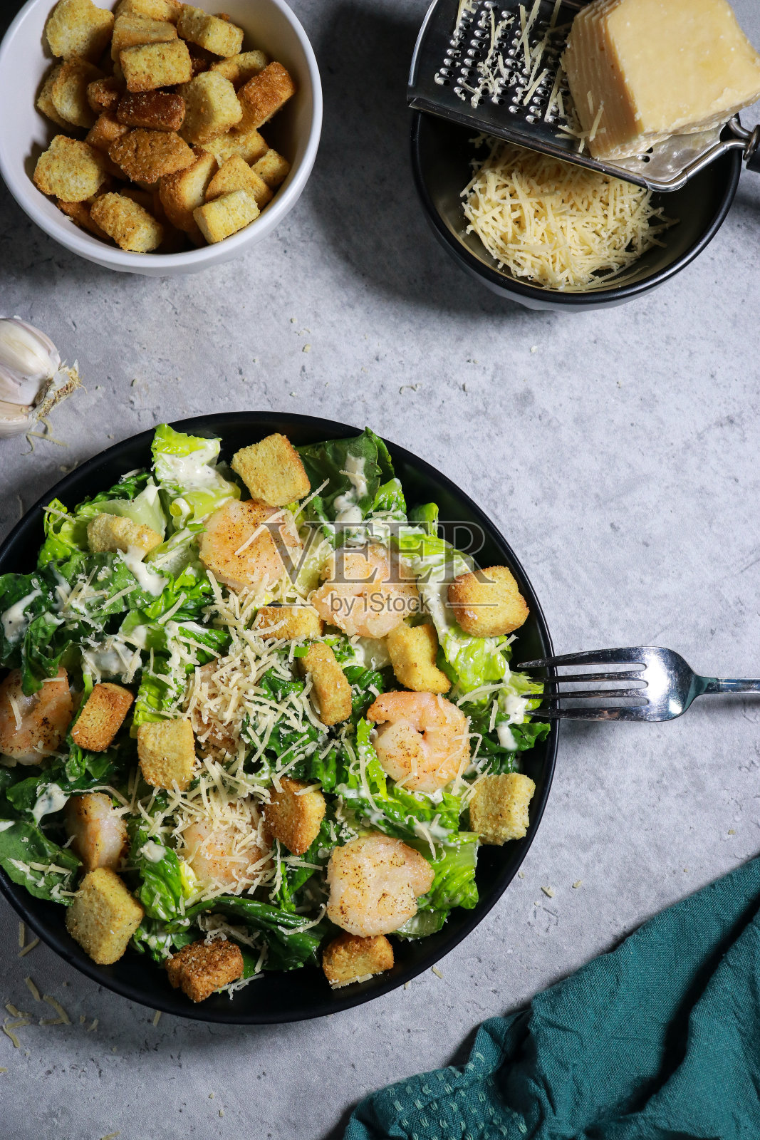 凯撒沙拉配烤虾，面包丁和帕尔马干酪放在灰色大理石桌上照片摄影图片