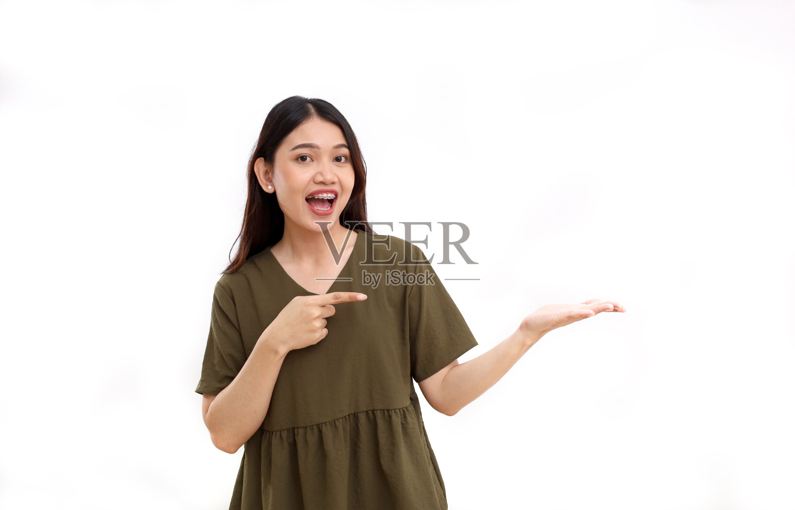 快乐的年轻亚洲女人站着，手里拿着，指着什么东西。孤立在白色背景中照片摄影图片