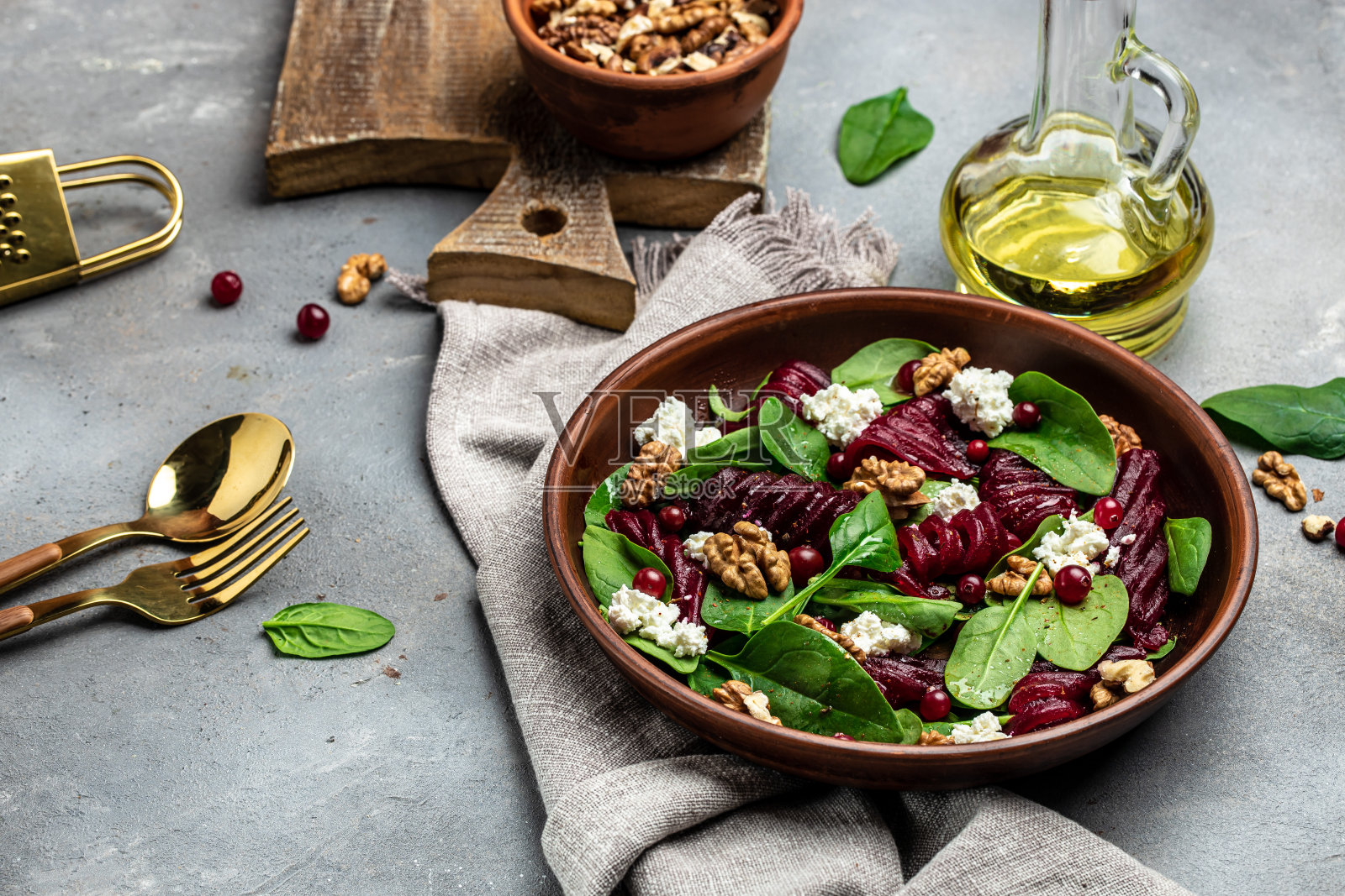 甜菜或甜菜根沙拉与婴儿菠菜，奶酪，坚果，小红莓在盘子上用叉子，调味品和香料在灰色背景，俯视图。放置文本的地方照片摄影图片