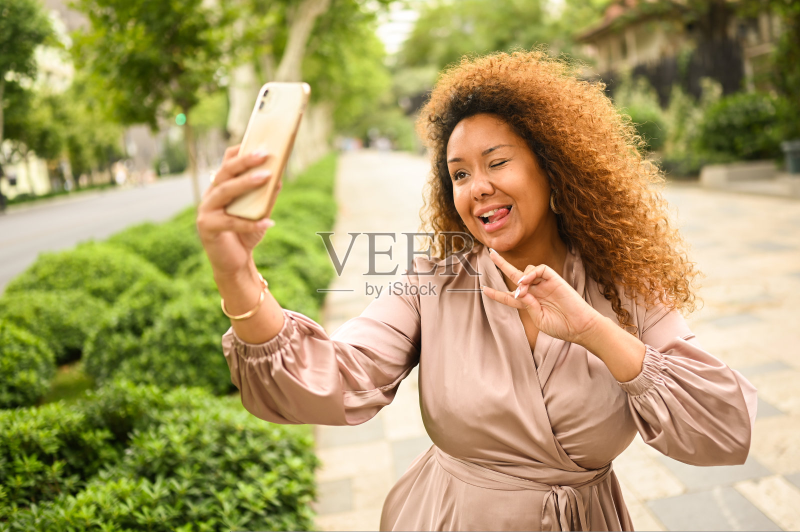 迷人的快乐时尚加上大小非裔美国女学生自由职业者非洲发型制作自拍与智能手机外面。夏天，在大城市的大街上，穿着丝绸衣服的年轻女子。多样性照片摄影图片