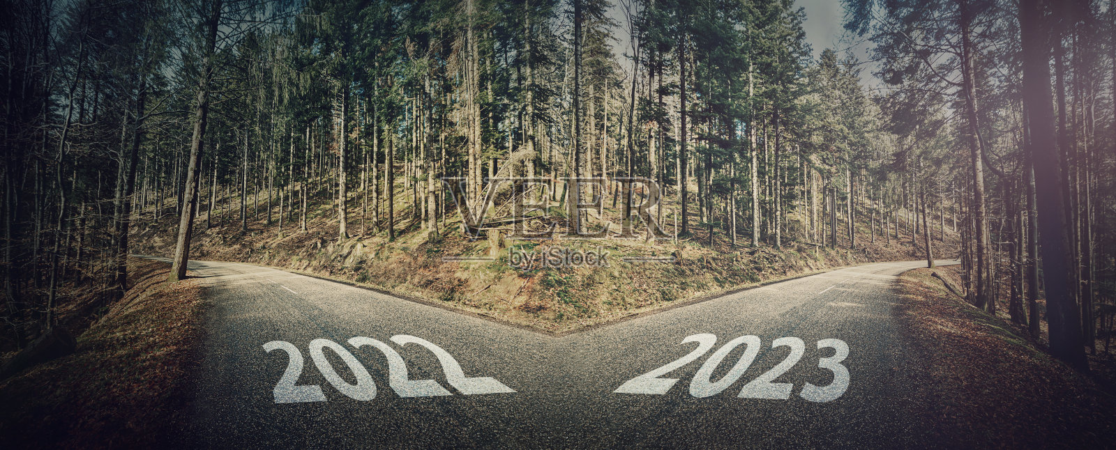 2022年和2023年十字路口的情景。柏油路穿过森林分成两个方向，左右，选择你的路。不同的课程，过去和未来，决定性的选择概念照片摄影图片