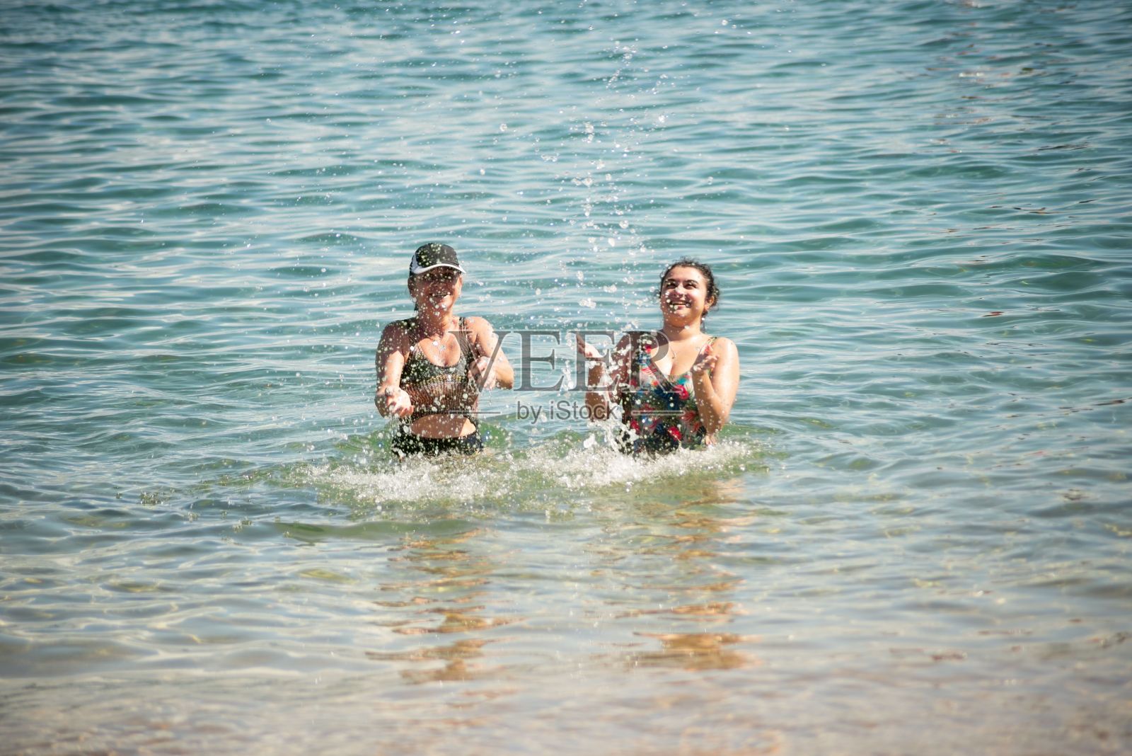 妇女在巴伊亚州萨尔瓦多港达巴拉海滩上泼水照片摄影图片