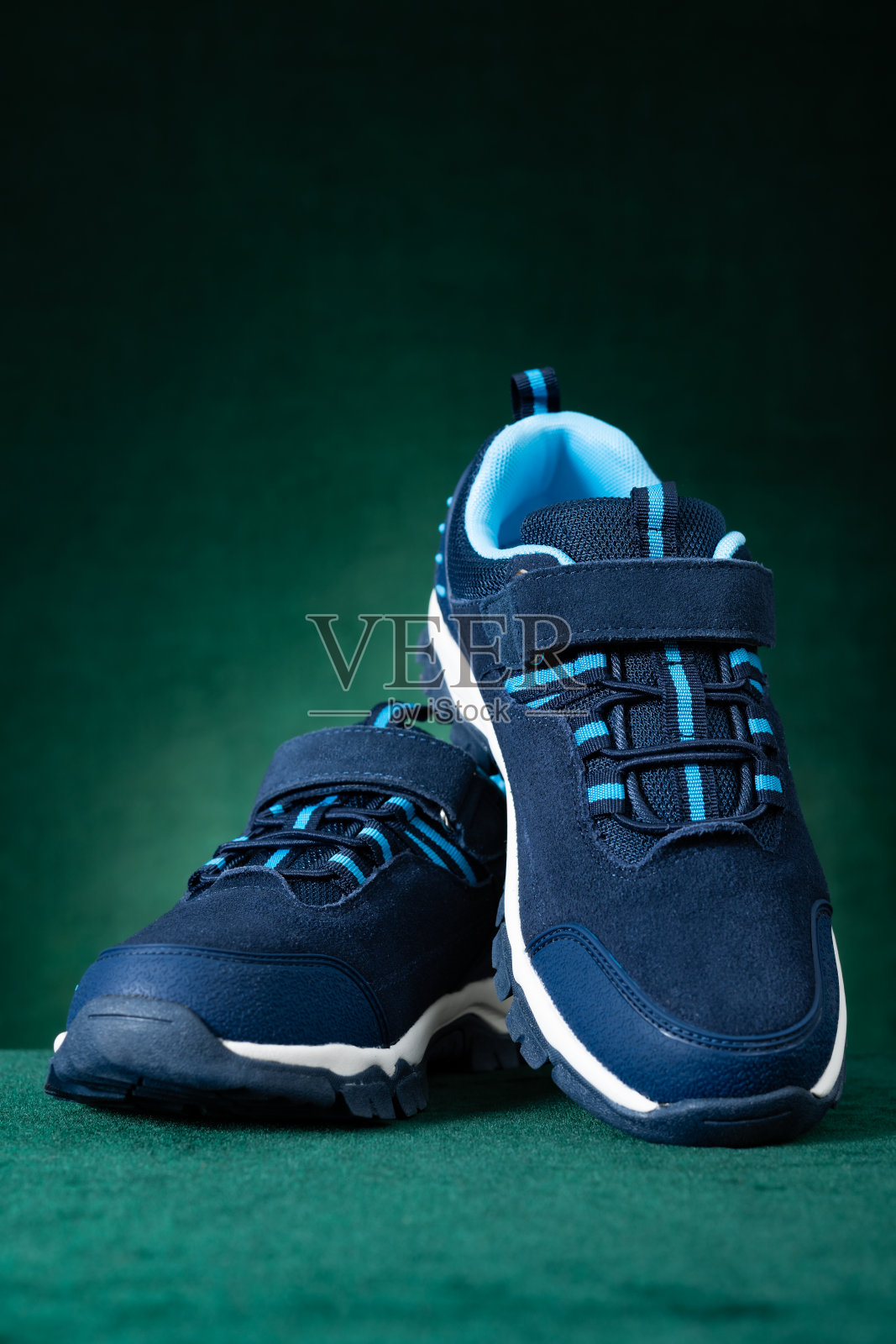 一双黑色和白色的运动鞋为孩子在绿色背景垂直组成照片摄影图片