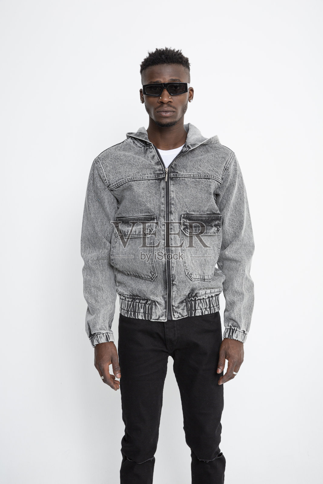黑人男模特戴着墨镜，穿着牛仔夹克，站在白色背景前。照片摄影图片