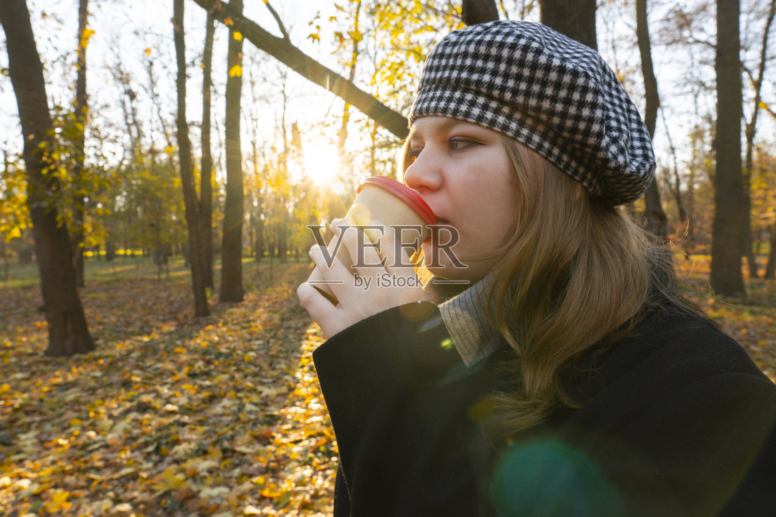 日落。城市公园。女孩用一次性杯子喝咖啡照片摄影图片