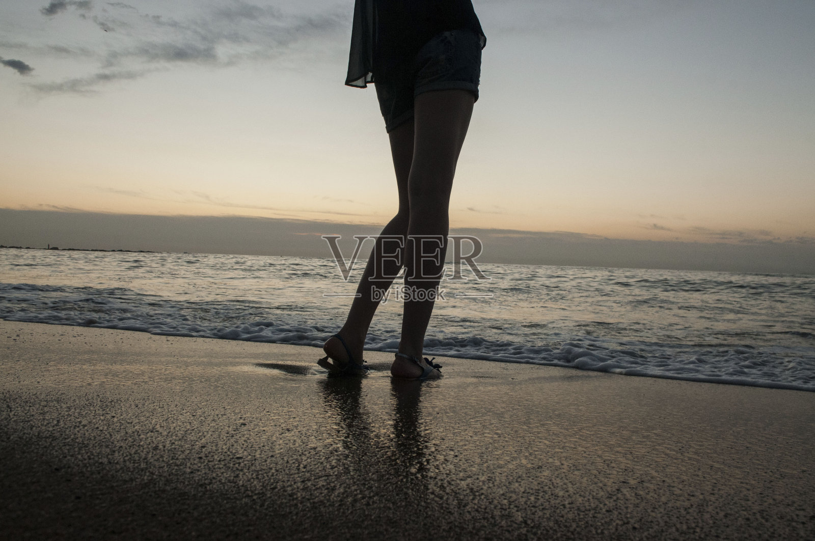 一个年轻女孩的腿在大海和沙滩上照片摄影图片