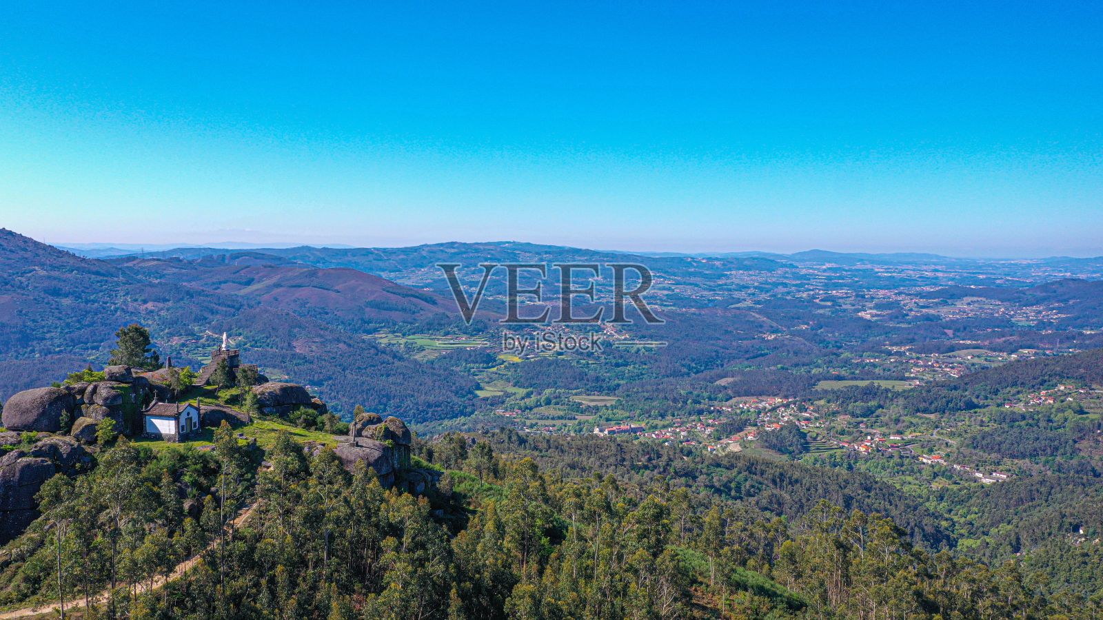 天空晴朗，树木覆盖的绿色景观的鸟瞰图照片摄影图片