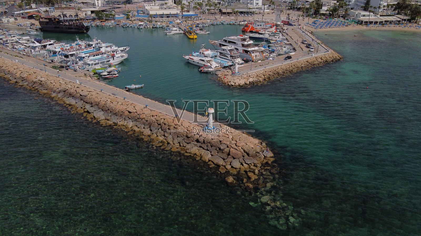 阳光明媚的一天，船只停泊在港口，映衬着蓝绿色的大海照片摄影图片